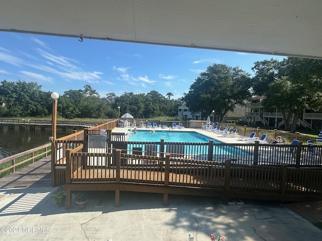 community pool featuring a water view, fence, and a patio