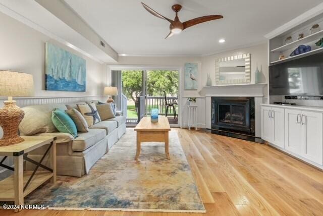 living area with recessed lighting, a glass covered fireplace, a ceiling fan, and light wood-style floors