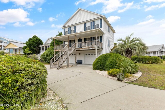 view of front of property with a porch, a garage, and a front lawn