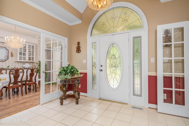 entryway featuring french doors, light tile patterned flooring, a chandelier, and ornamental molding