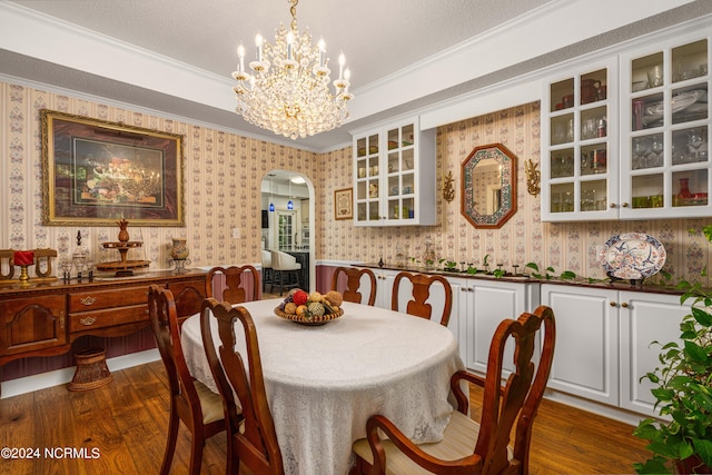 dining room with a textured ceiling, dark hardwood / wood-style flooring, crown molding, and a chandelier