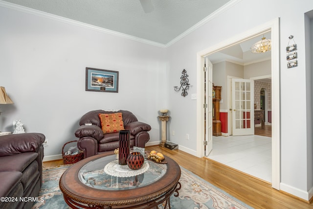 living room with a textured ceiling, french doors, a chandelier, hardwood / wood-style flooring, and crown molding