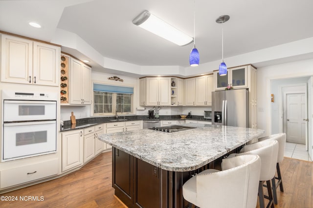 kitchen with hanging light fixtures, wood-type flooring, appliances with stainless steel finishes, and a kitchen island