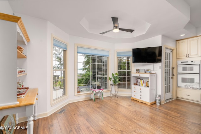 interior space featuring light wood-type flooring, ceiling fan, double oven, and cream cabinets