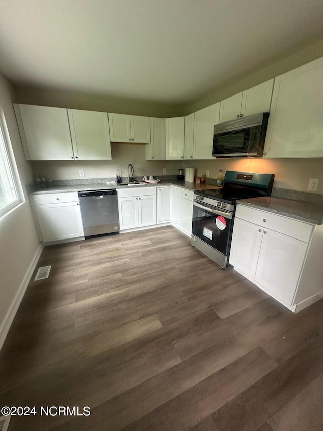 kitchen featuring a sink, white cabinetry, baseboards, appliances with stainless steel finishes, and dark wood finished floors