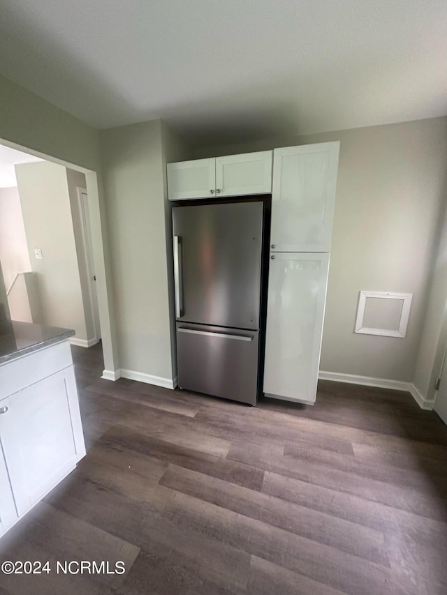 kitchen with dark hardwood / wood-style flooring, stainless steel refrigerator, and white cabinetry