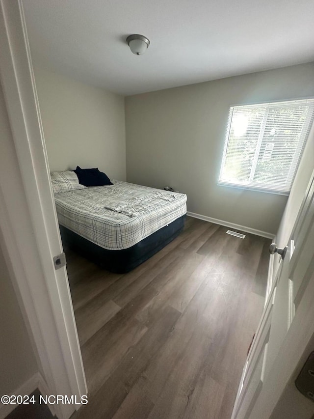 bedroom with baseboards, visible vents, and dark wood-type flooring