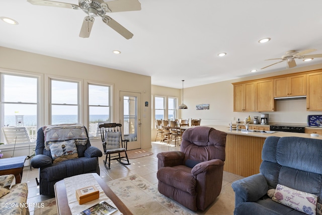 living room featuring ceiling fan, sink, a water view, and light tile patterned flooring