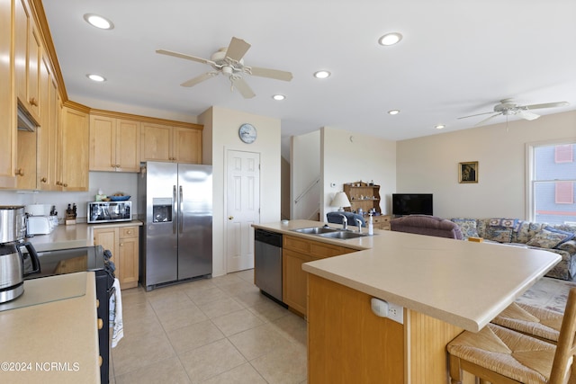 kitchen featuring appliances with stainless steel finishes, a kitchen island with sink, light brown cabinetry, and sink