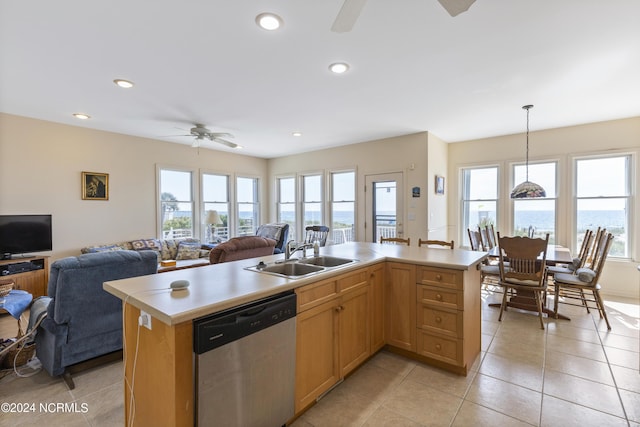 kitchen with stainless steel dishwasher, decorative light fixtures, sink, and a kitchen island with sink