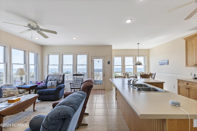 kitchen featuring decorative light fixtures, light brown cabinets, a center island with sink, and sink