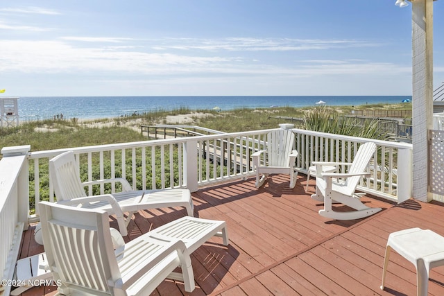 wooden terrace featuring a water view and a view of the beach