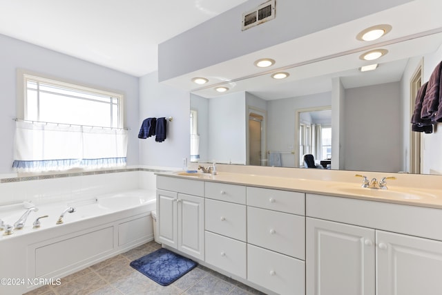 bathroom with tile patterned flooring, a bath, and vanity