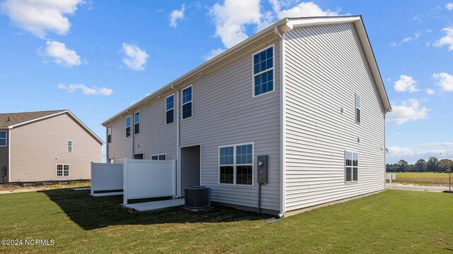 rear view of property with a lawn and central air condition unit