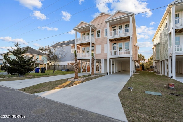 coastal home with a carport, concrete driveway, and a front lawn