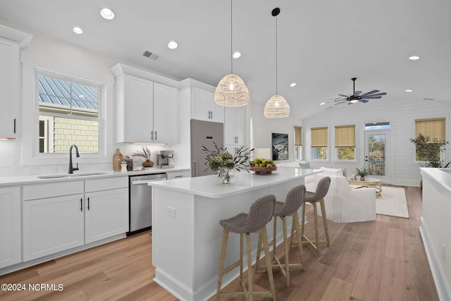 kitchen with white cabinets, hanging light fixtures, sink, and appliances with stainless steel finishes