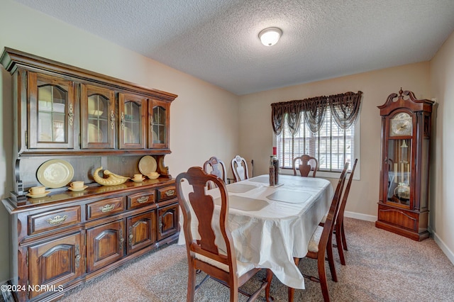 dining space featuring light colored carpet and a textured ceiling