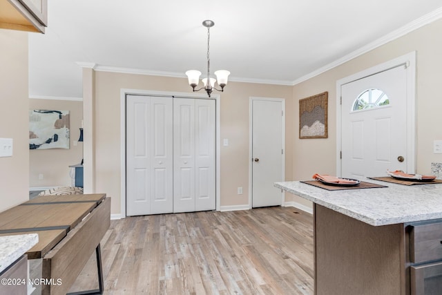 foyer featuring light wood finished floors, baseboards, ornamental molding, and a notable chandelier