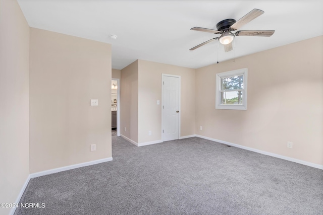 carpeted spare room with a ceiling fan and baseboards
