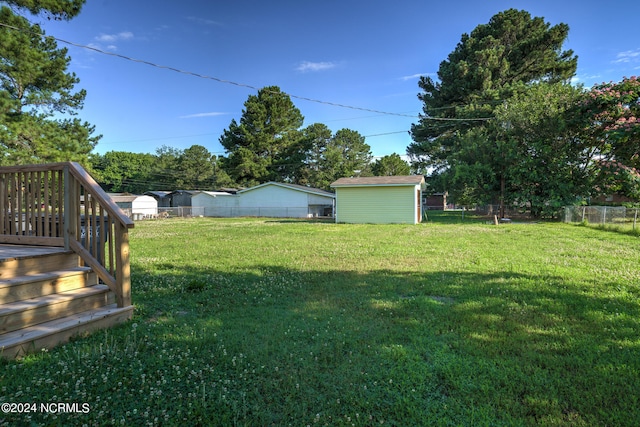 view of yard featuring a wooden deck and a storage shed