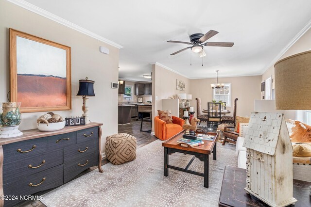 living room with wood-type flooring, crown molding, and ceiling fan with notable chandelier