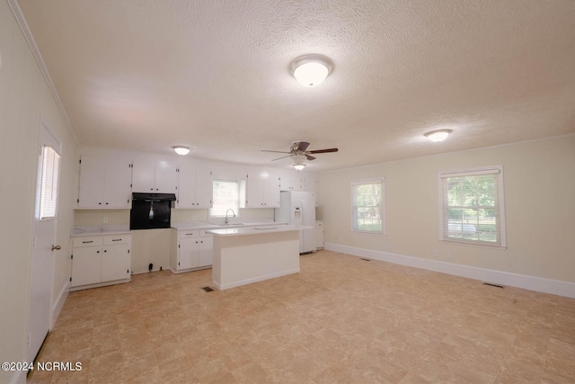 kitchen featuring ceiling fan, a center island, sink, white refrigerator with ice dispenser, and white cabinets