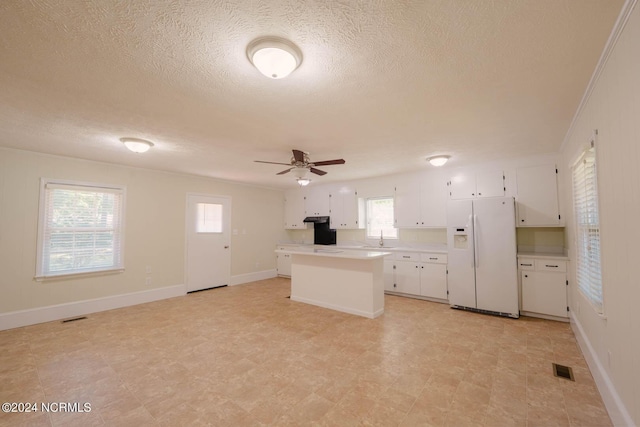 kitchen featuring a center island, white refrigerator with ice dispenser, sink, ceiling fan, and white cabinetry