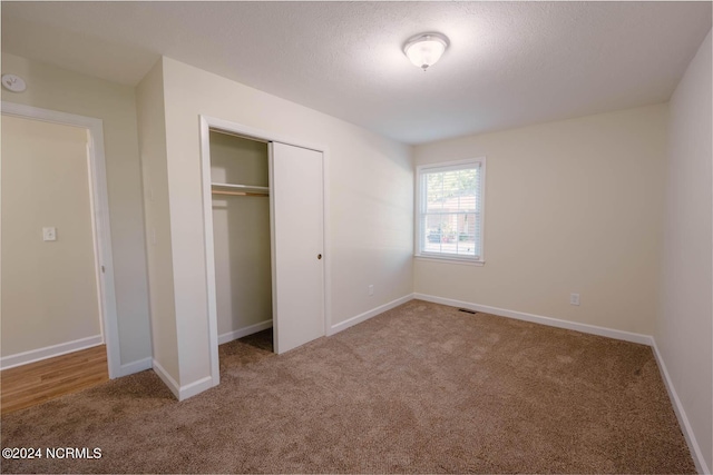 unfurnished bedroom with carpet flooring, a closet, and a textured ceiling