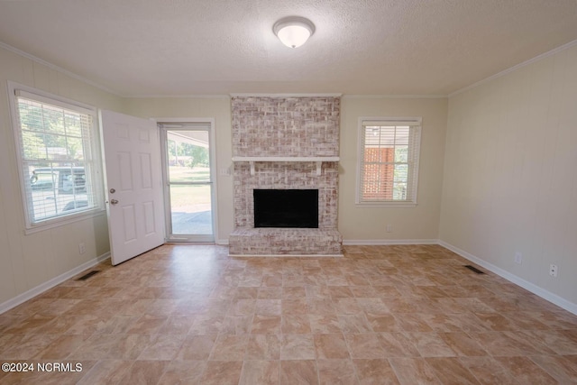 unfurnished living room with a wealth of natural light, crown molding, a fireplace, and a textured ceiling