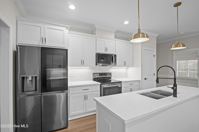 kitchen featuring appliances with stainless steel finishes, a sink, white cabinetry, and crown molding