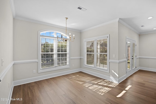 unfurnished dining area with baseboards, visible vents, ornamental molding, wood finished floors, and a chandelier