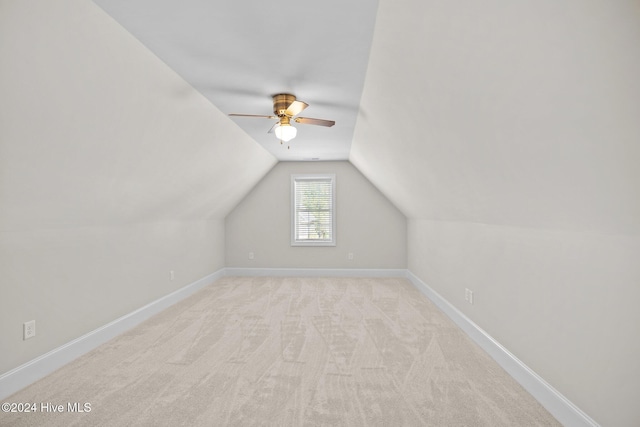 additional living space featuring light colored carpet, vaulted ceiling, baseboards, and ceiling fan