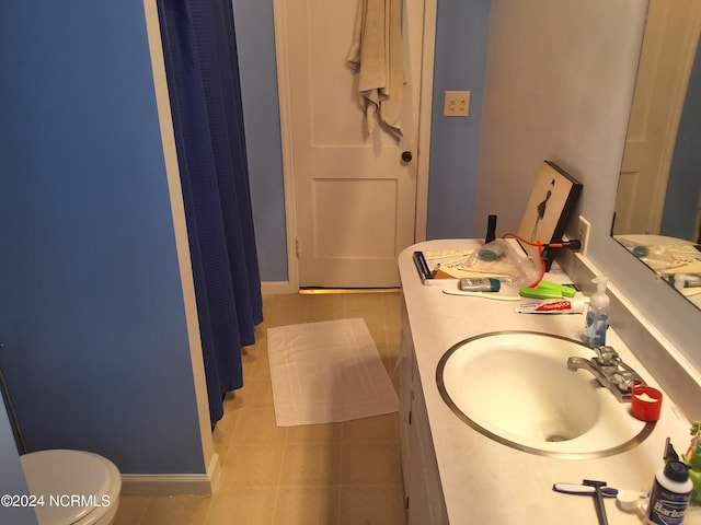 bathroom with toilet, vanity, and tile patterned floors