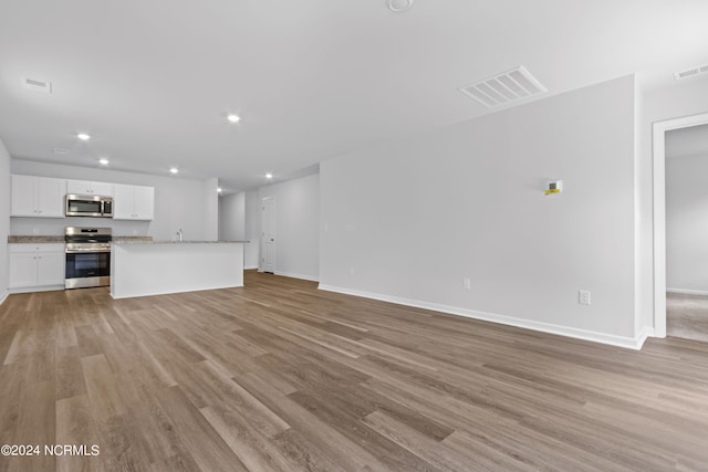 unfurnished living room featuring light wood-type flooring and sink