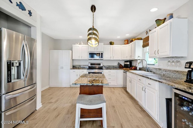 kitchen with appliances with stainless steel finishes, wine cooler, a sink, and white cabinetry