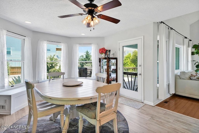 dining space featuring a textured ceiling, ceiling fan, light wood-style flooring, and baseboards