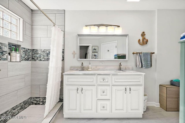 full bathroom featuring double vanity, a sink, and tiled shower