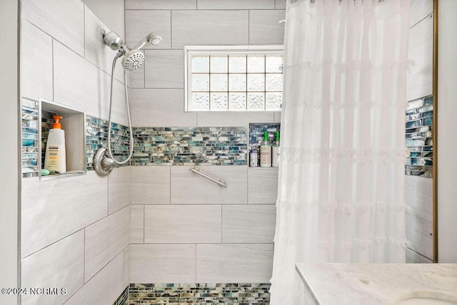 full bathroom with a tile shower and vanity