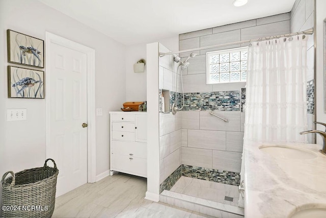 bathroom featuring double vanity, a stall shower, and a sink