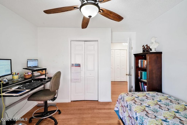 bedroom featuring a ceiling fan, a closet, baseboards, and wood finished floors