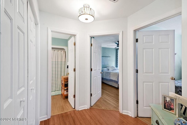 hallway with light wood-style flooring and baseboards