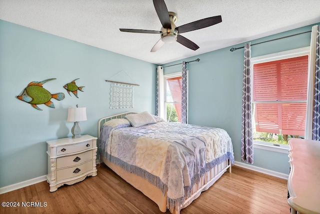 bedroom with a ceiling fan, light wood-type flooring, a textured ceiling, and baseboards