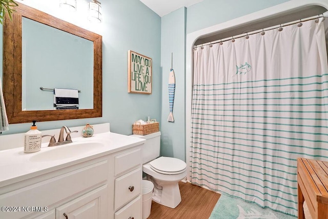 full bathroom featuring toilet, a shower with shower curtain, wood finished floors, and vanity