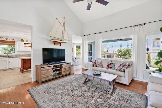 living room with light wood-type flooring, ceiling fan, and high vaulted ceiling