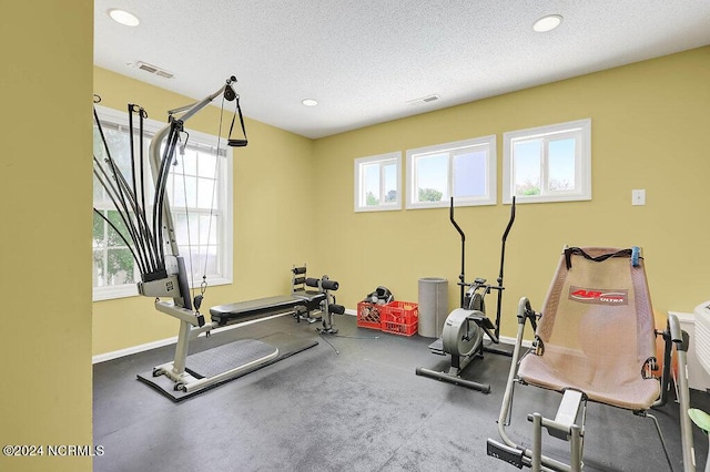 workout area with baseboards, visible vents, a textured ceiling, and recessed lighting