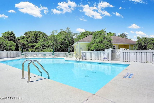 pool with a patio area and fence