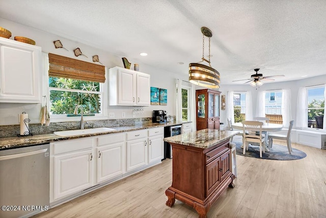 kitchen featuring a sink, light wood finished floors, stone countertops, and dishwasher