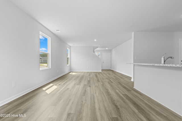 unfurnished living room with sink and light hardwood / wood-style floors