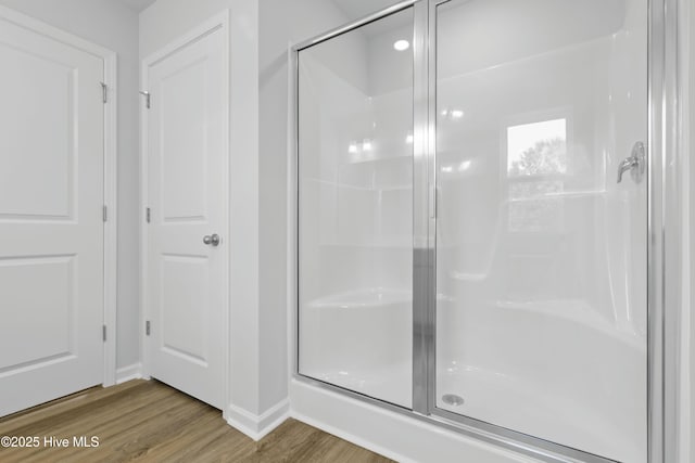 bathroom with wood-type flooring and a shower with shower door