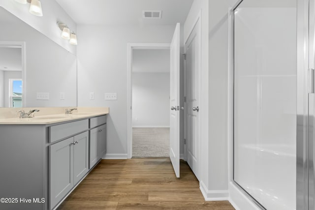 bathroom featuring hardwood / wood-style flooring, vanity, and walk in shower